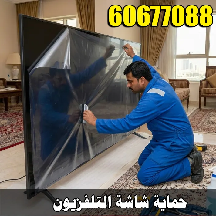 فني متخصص بملامح هندية يرتدي زي عمل أزرق، يقوم بتركيز شديد بتركيب طبقة حماية شفافة على شاشة تلفزيون مسطحة كبيرة الحجم داخل غرفة معيشة في منزل كويتي.